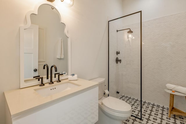 bathroom featuring a tile shower, vanity, and toilet