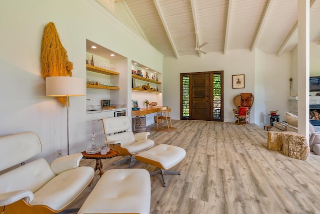 sitting room with built in shelves, ceiling fan, light hardwood / wood-style flooring, wooden ceiling, and vaulted ceiling with beams