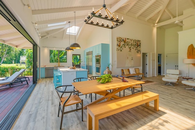 dining space with a skylight, light hardwood / wood-style flooring, high vaulted ceiling, and beamed ceiling