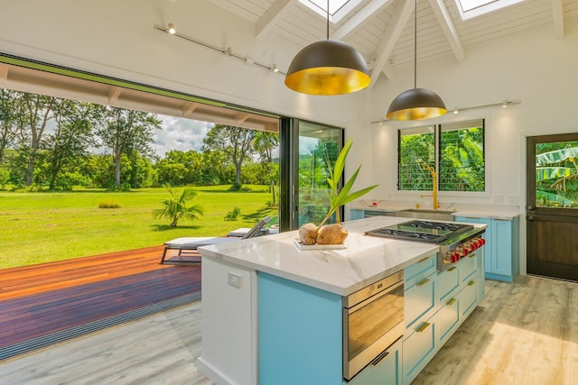 kitchen featuring beam ceiling, a skylight, light hardwood / wood-style flooring, and decorative light fixtures