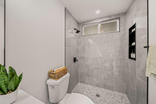 bathroom with a tile shower and toilet