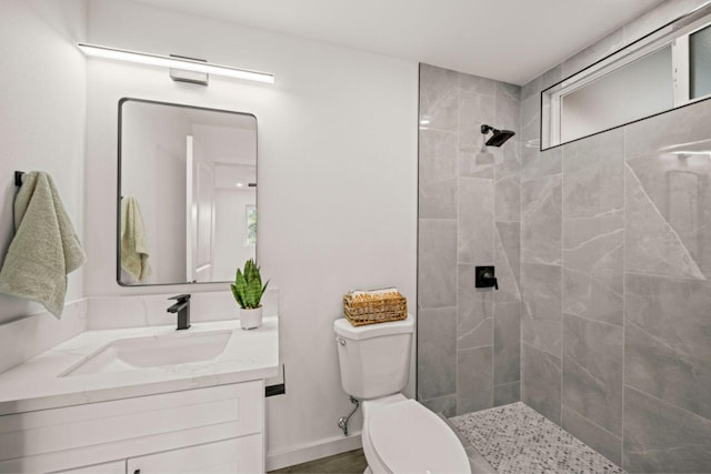 bathroom featuring vanity, toilet, and a tile shower