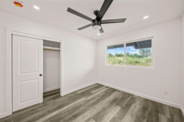 unfurnished bedroom with ceiling fan, a closet, and dark wood-type flooring