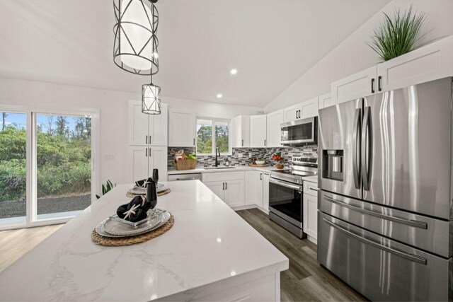 kitchen with pendant lighting, tasteful backsplash, light stone counters, white cabinetry, and stainless steel appliances