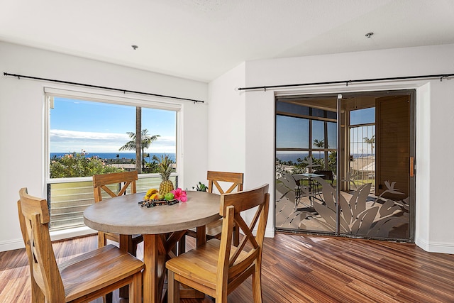 dining area featuring dark hardwood / wood-style flooring and a water view