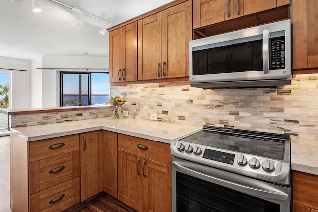 kitchen with appliances with stainless steel finishes, tasteful backsplash, and light stone counters