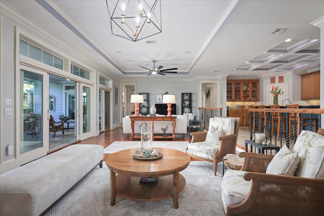 living room with hardwood / wood-style floors, french doors, coffered ceiling, ceiling fan with notable chandelier, and crown molding