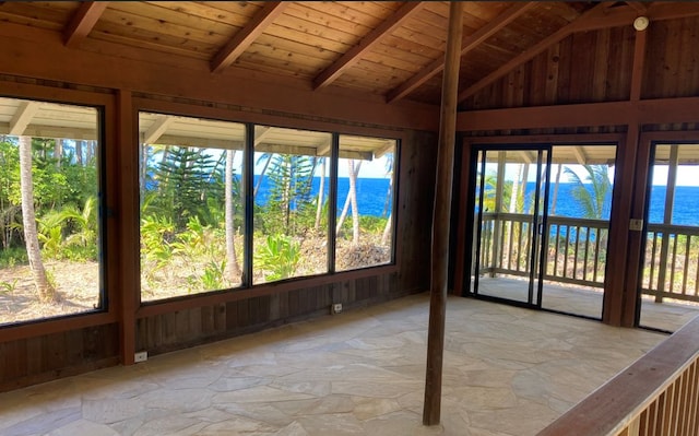 unfurnished sunroom with lofted ceiling with beams, a water view, wooden ceiling, and a wealth of natural light