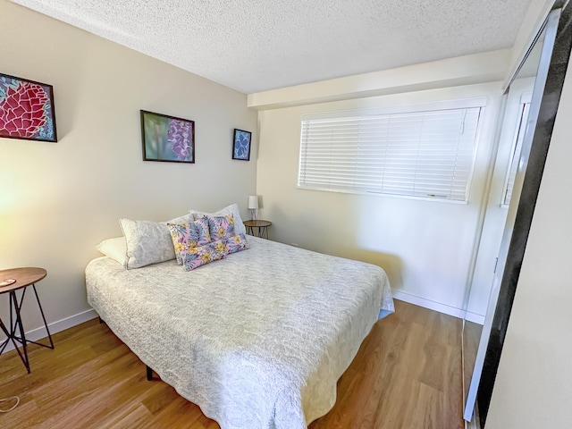 bedroom featuring a textured ceiling and light hardwood / wood-style flooring