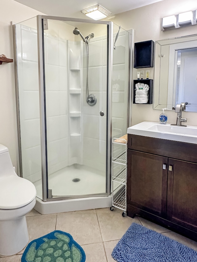 bathroom with tile patterned floors, a shower with door, vanity, and toilet