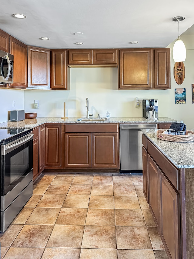 kitchen featuring light stone countertops, sink, decorative light fixtures, and appliances with stainless steel finishes