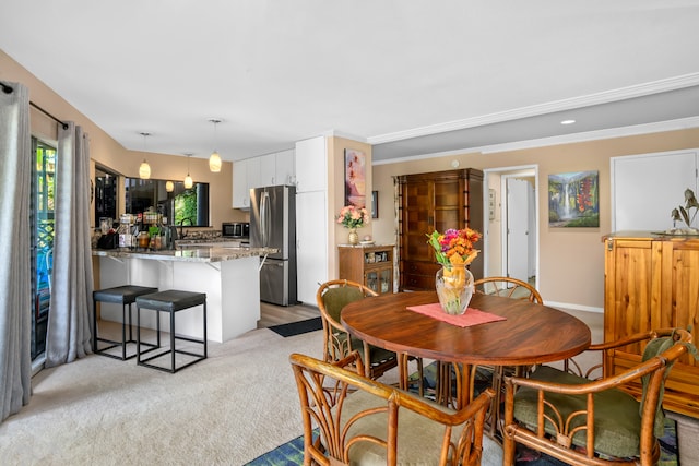 carpeted dining space featuring crown molding and sink