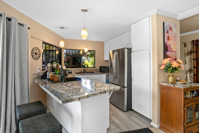 kitchen featuring kitchen peninsula, sink, dark stone countertops, appliances with stainless steel finishes, and white cabinetry