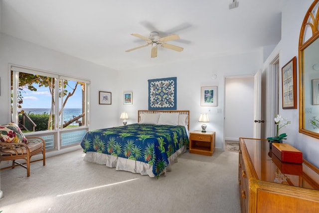 bedroom with ceiling fan, a water view, and light colored carpet