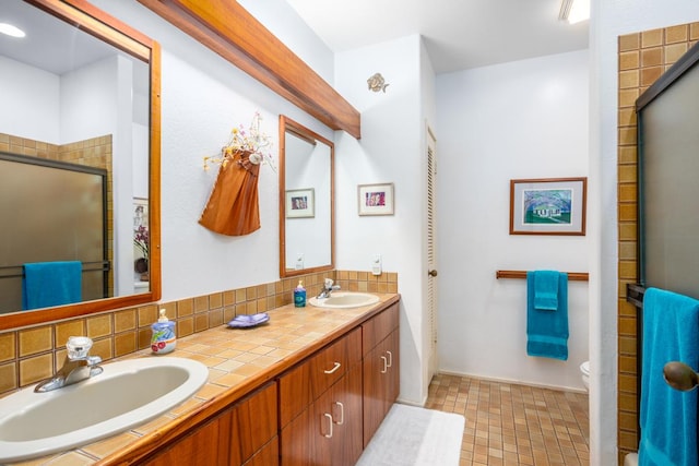 bathroom with backsplash, vanity, and an enclosed shower