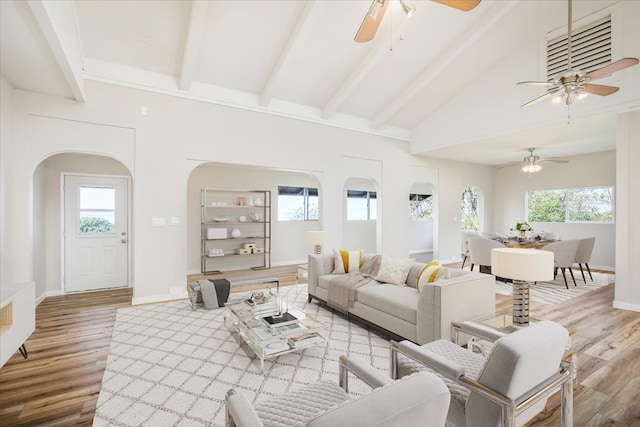 living room with beamed ceiling, high vaulted ceiling, and light hardwood / wood-style flooring