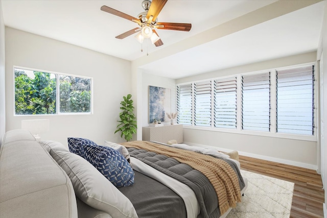 bedroom featuring hardwood / wood-style flooring, ceiling fan, and multiple windows