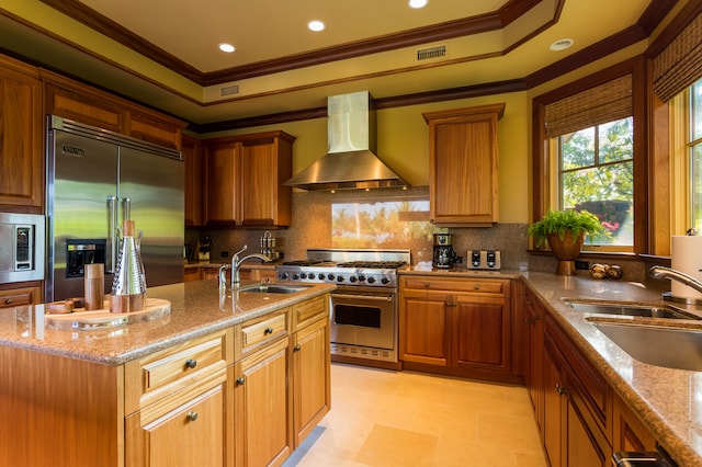 kitchen with built in appliances, wall chimney exhaust hood, sink, and crown molding