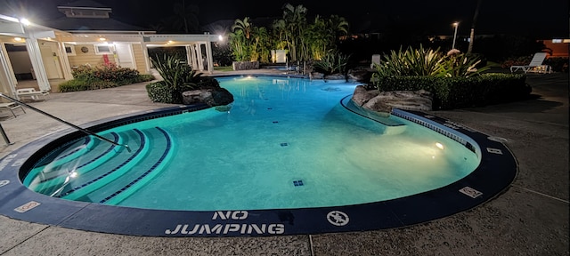 pool at night with a patio area