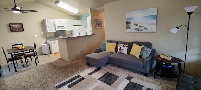 carpeted living room with ceiling fan and vaulted ceiling