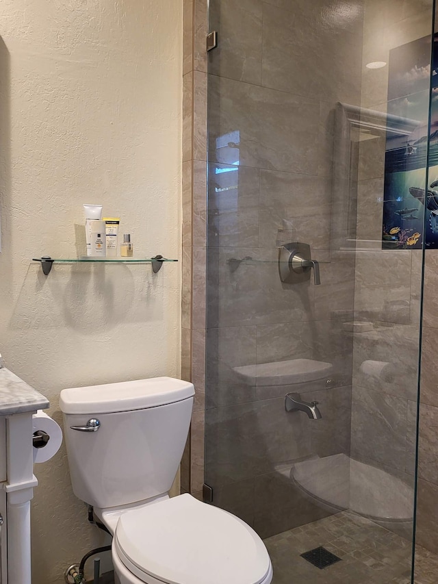 bathroom featuring vanity, toilet, and tiled shower