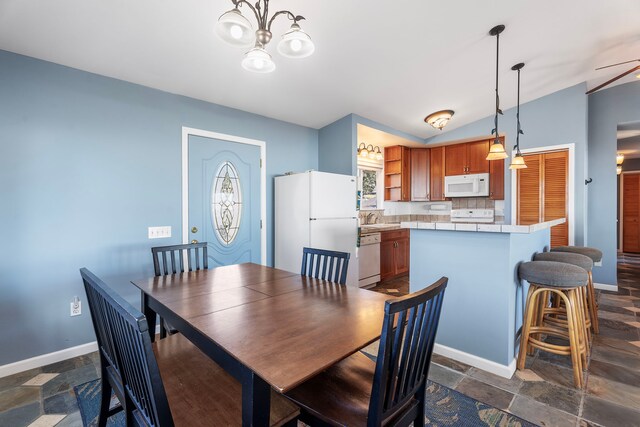 dining room featuring ceiling fan with notable chandelier, a healthy amount of sunlight, lofted ceiling, and sink