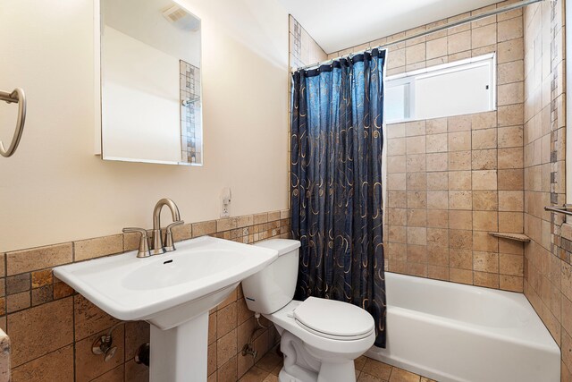 bathroom with tile patterned flooring, shower / bath combo, tile walls, and toilet