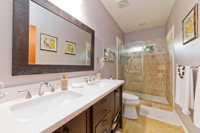 bathroom with tile patterned floors, vanity, toilet, and tiled shower