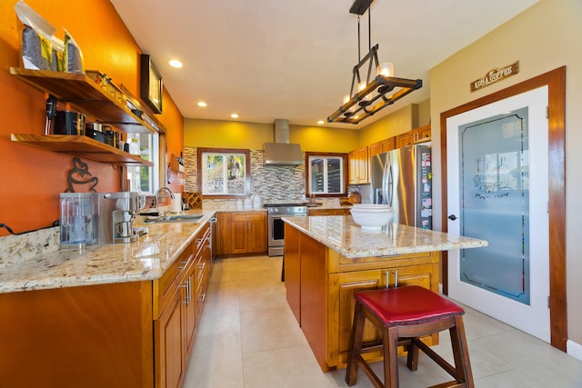 kitchen featuring a center island, sink, wall chimney exhaust hood, appliances with stainless steel finishes, and decorative light fixtures