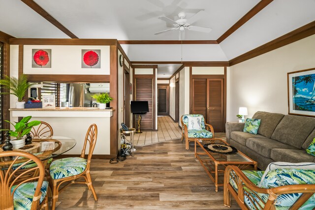 living room featuring wood-type flooring, vaulted ceiling, ceiling fan, and ornamental molding