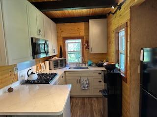 kitchen featuring kitchen peninsula, appliances with stainless steel finishes, sink, beamed ceiling, and white cabinets