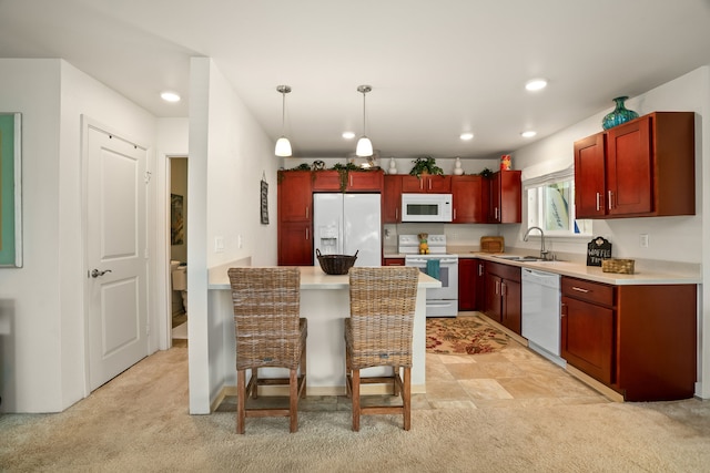 kitchen with white appliances, light carpet, sink, hanging light fixtures, and a breakfast bar area