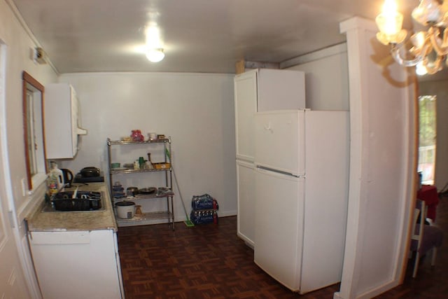 kitchen with white cabinets, dark parquet flooring, white appliances, and sink