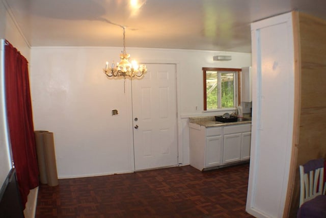 interior space with dark parquet flooring, sink, and an inviting chandelier