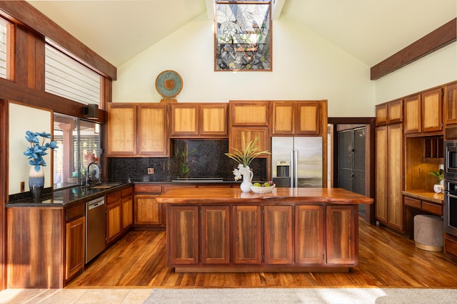 kitchen featuring tasteful backsplash, stainless steel appliances, sink, high vaulted ceiling, and a center island