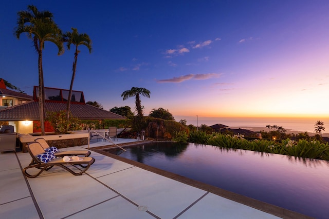 pool at dusk featuring a patio