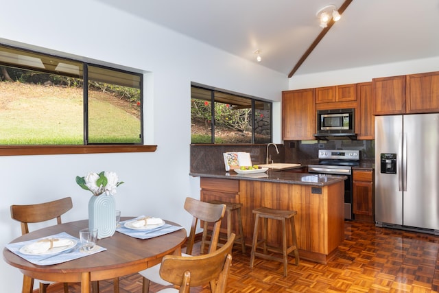 kitchen featuring backsplash, a kitchen breakfast bar, vaulted ceiling with beams, appliances with stainless steel finishes, and kitchen peninsula