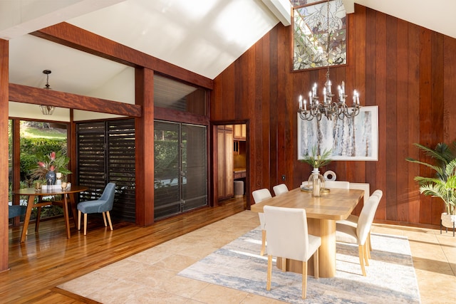 dining area featuring high vaulted ceiling, wooden walls, light tile patterned floors, a notable chandelier, and beam ceiling