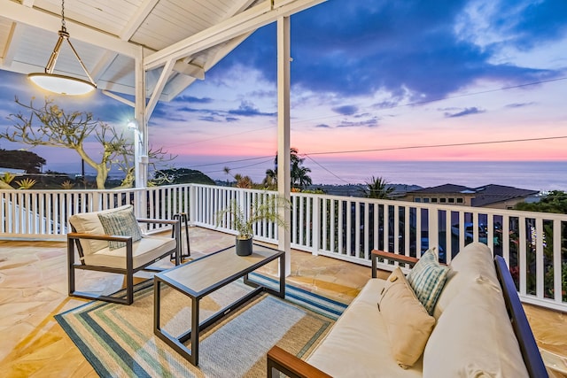 deck at dusk with outdoor lounge area and a water view