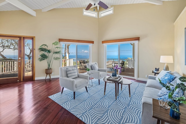 living room featuring beamed ceiling, hardwood / wood-style floors, ceiling fan, and a high ceiling