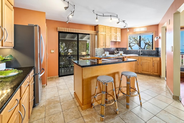 kitchen with a breakfast bar, light brown cabinetry, tasteful backsplash, and light tile patterned flooring