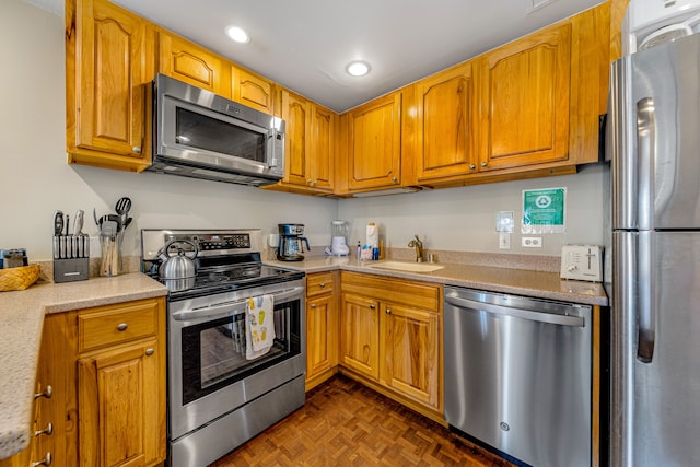 kitchen with dark parquet flooring, sink, and appliances with stainless steel finishes