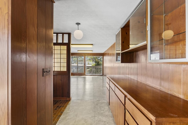 hall featuring light tile patterned flooring and wooden walls