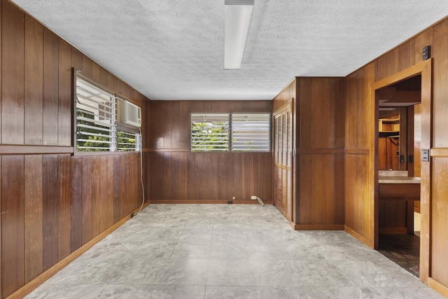 spare room with a textured ceiling and wooden walls