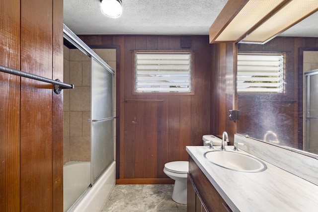 full bathroom with bath / shower combo with glass door, vanity, a textured ceiling, and wooden walls