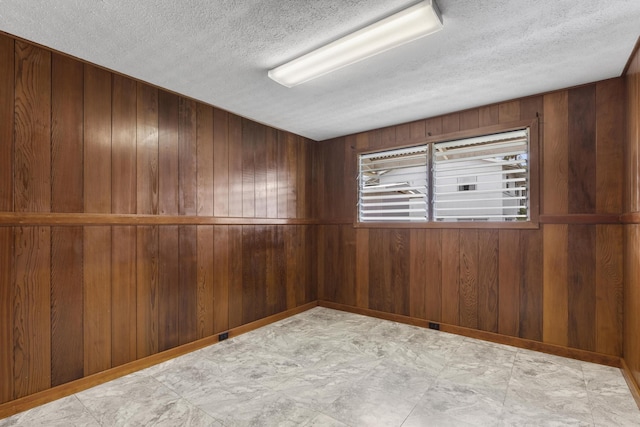 unfurnished room with wood walls and a textured ceiling