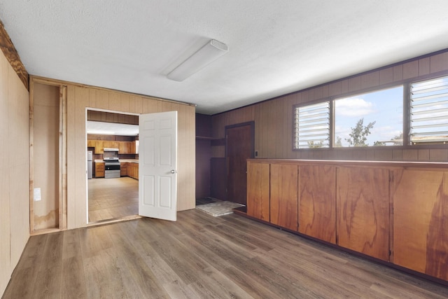 unfurnished room featuring a textured ceiling, dark hardwood / wood-style flooring, and wooden walls