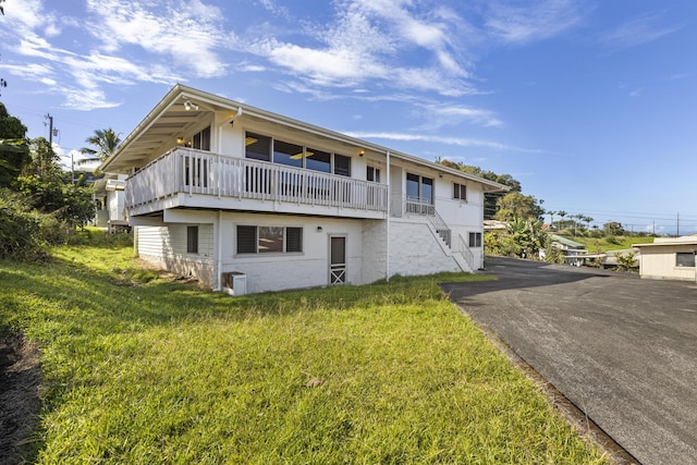 back of house featuring a balcony and a yard