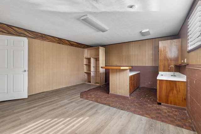 bar featuring a textured ceiling, wooden walls, and sink