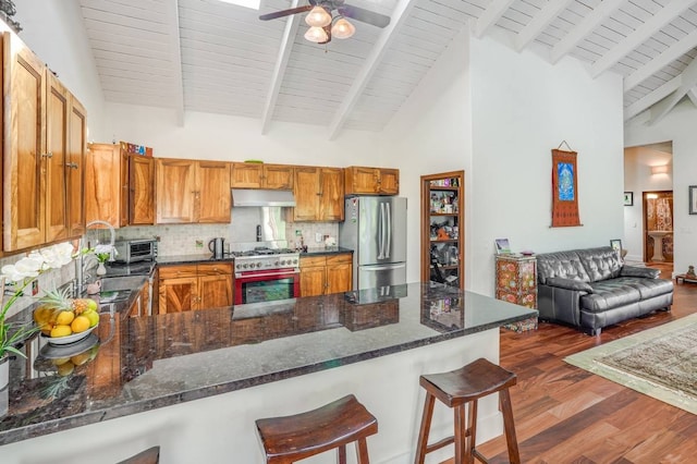 kitchen with a kitchen bar, dark hardwood / wood-style flooring, kitchen peninsula, and stainless steel appliances